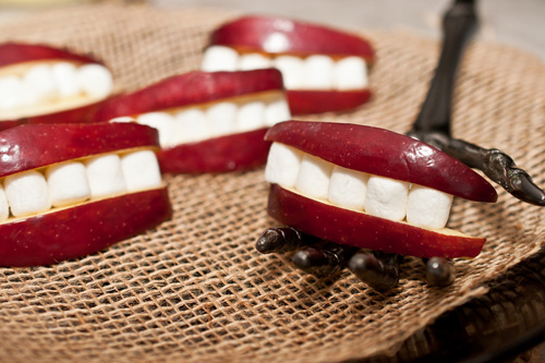 five apple marshmallow teeth, one on a skeleton hand