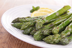 cooked asparagus spears on a plate with lemon and mint