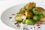 brussels sprouts on a plate with bacon and crumbled white cheese