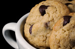 three chocolate chip cookies in a white ceramic cup