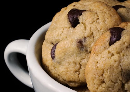 three chocolate chip cookies in a white ceramic cup