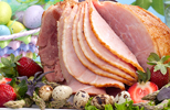 partially sliced ham on a plate next to an easter basket