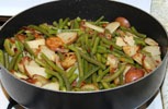 cooked green beans and fried potatoes in a skillet