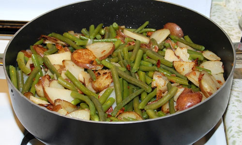 cooked green beans and fried potatoes in a skillet