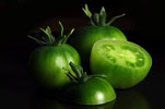 two whole raw green tomatoes and one with top cut off