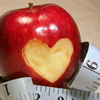 apple with a heart shaped bite out of it and a tape measure