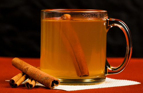 glass mug of hot apple cider with a cinnamon stick