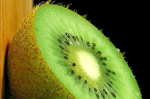 half an unpeeled raw kiwi fruit with black seeds