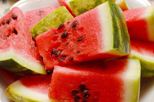 watermelon chunks with the rind on a white plate