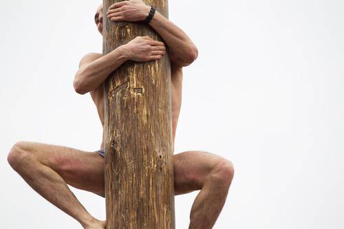 man climbing a pole with no clothing visible