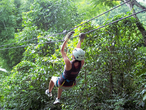 woman ziplining in the air through a forest